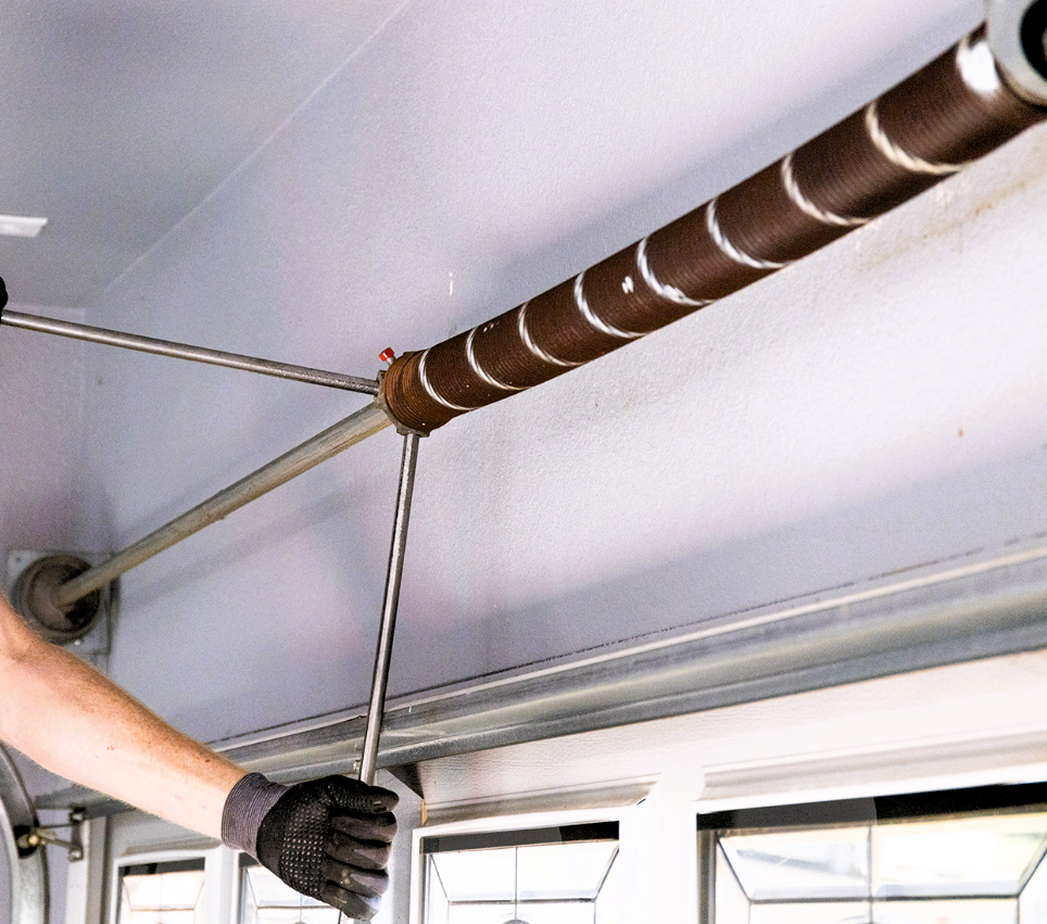 Technician performing garage door spring repair in Coral Springs for a residential home.