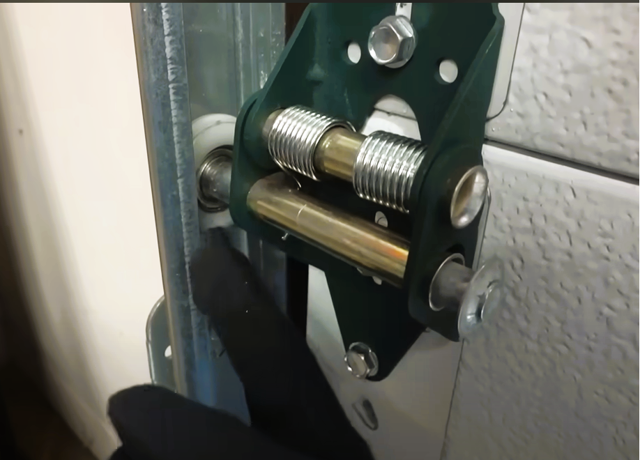 Technician fixing a noisy garage door in Coral Springs, focusing on the rollers and hinges for a smooth operation